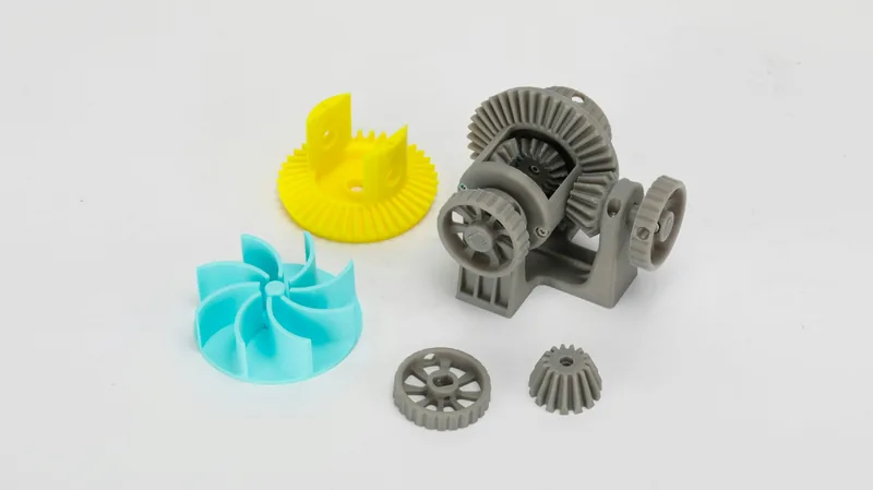 Engrenagens, rotor e um conjunto de redução impressos em 3D, em cinza, amarelo e azul