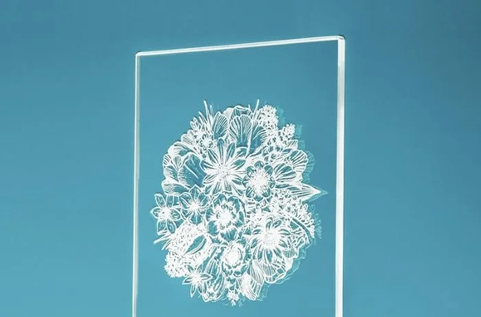 Placa de acrílico com desenho floral gravado, sobre fundo azul